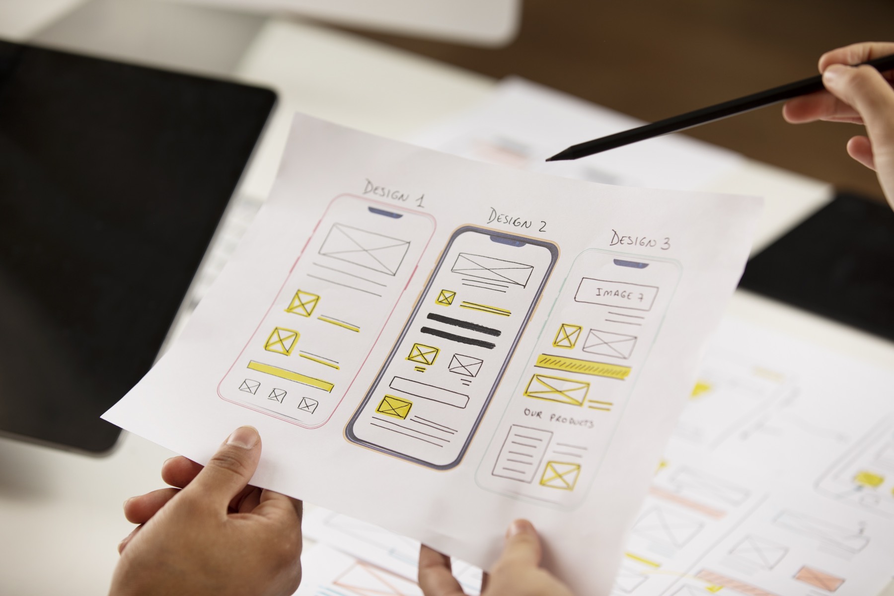 Three hand-drawn phone layout options sketched on paper, side by side